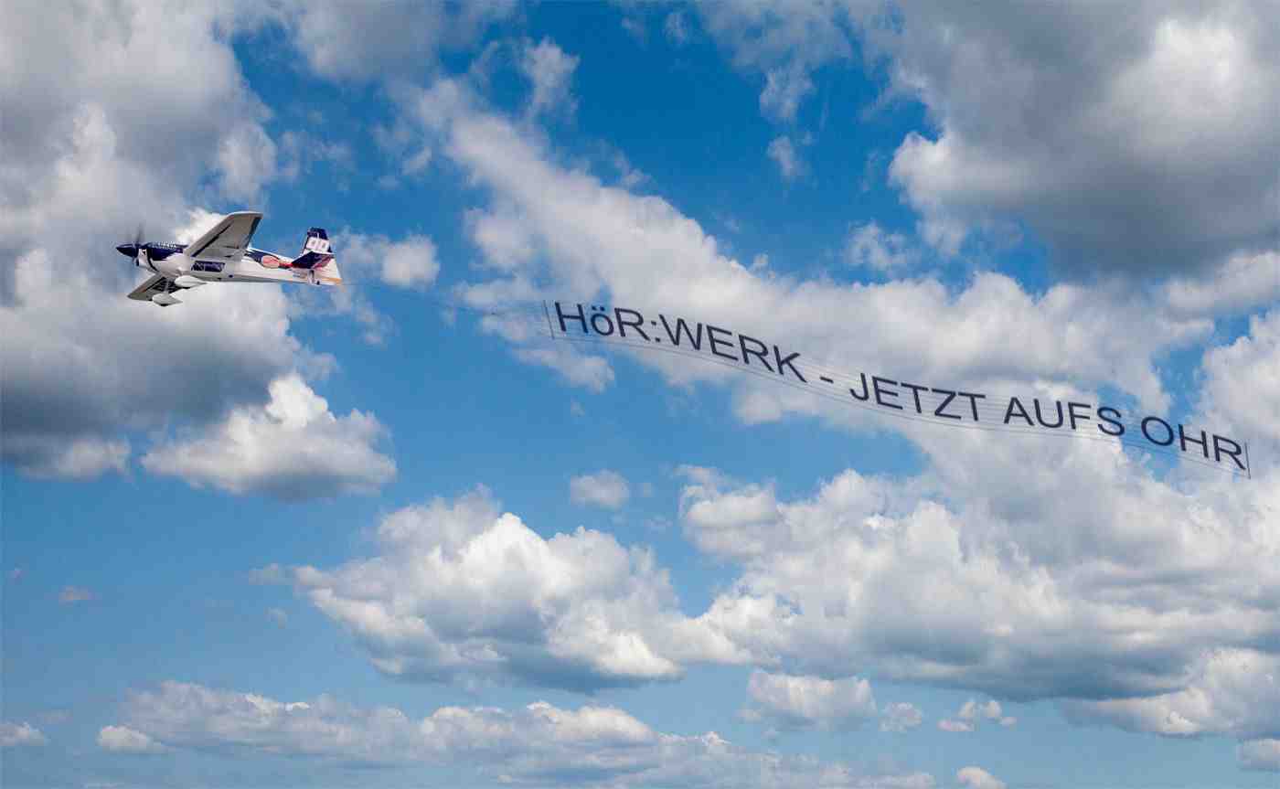 WERK - JETZT AUFS OHR vor bewölktem Himmel