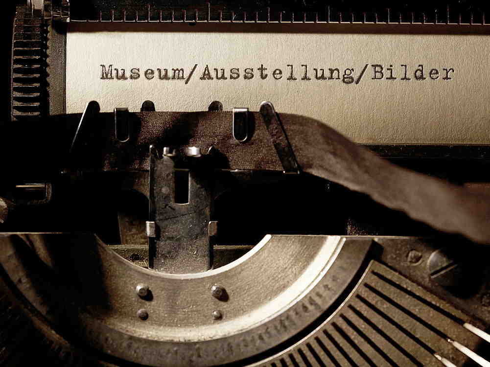 Alte Schreibmaschine mit Papier und den Worten Museum Ausstellung Bilder getippt