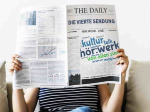 Person liest Zeitung mit Titel THE DAILY und Wortfeld zu kultur, hörwerk und talk.